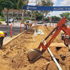 Landscapers using equipment to dig a trench